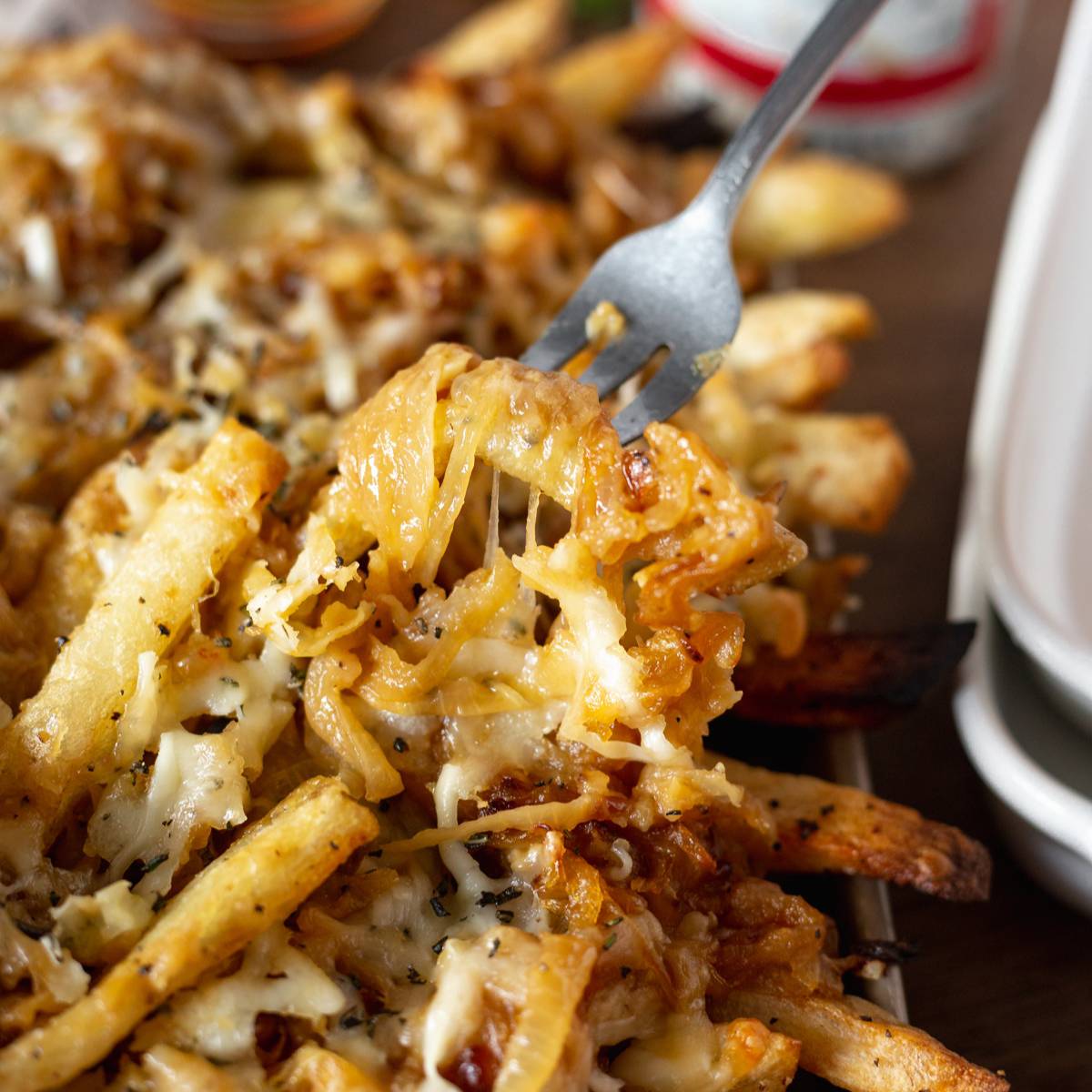 Close up shot of cheesy pull of french onion fries on a fork