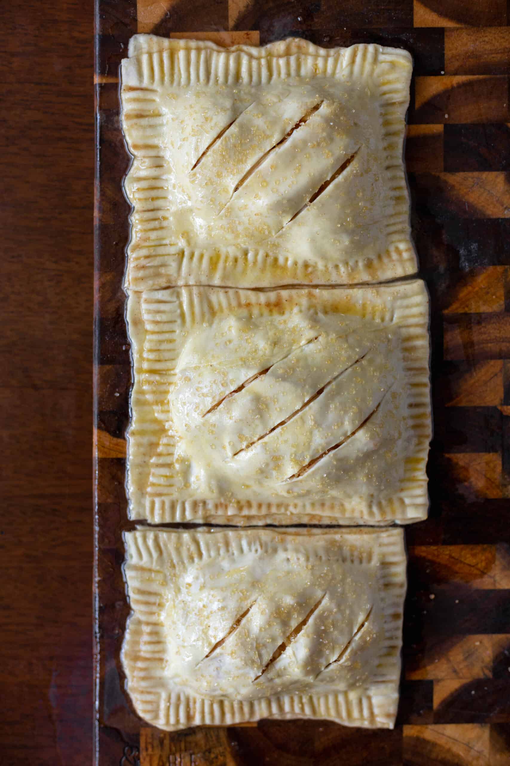 Prepared apple hand pies brushed in egg wash and cut on top