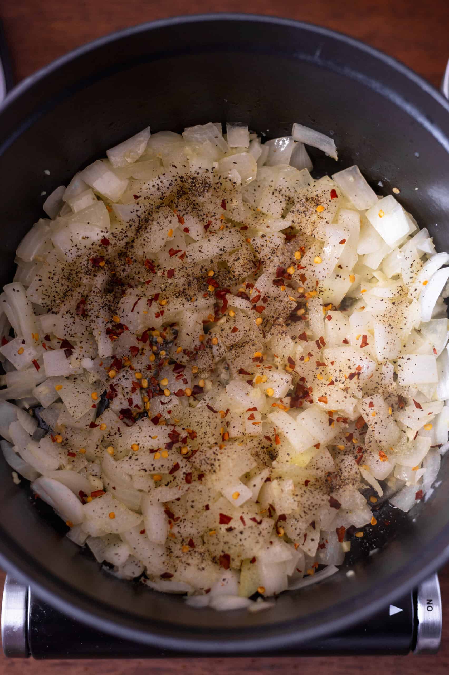 Red pepper flakes sprinkled on onion mixture in large dutch oven pot