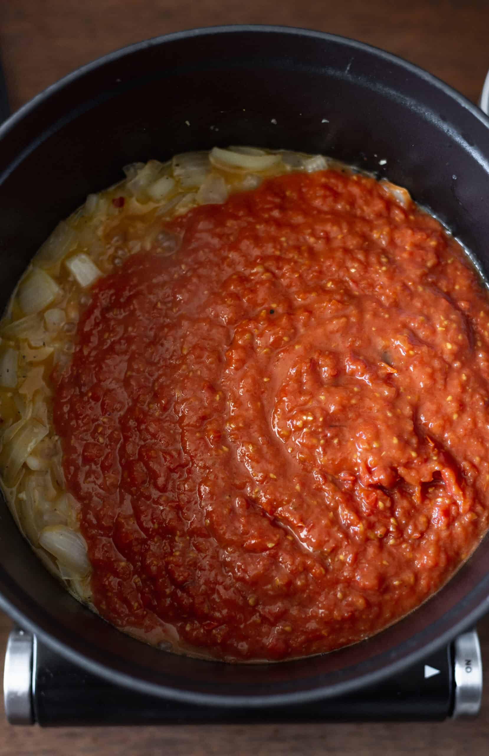 Tomato puree added to onion mixture in dutch oven