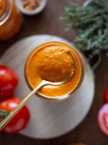 Creamy vodka sauce on a gold spoon in a jar
