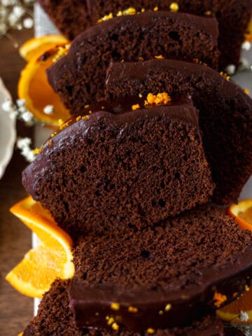 Orange Chocolate Fudge Loaf Cake slice surrounded by oranges
