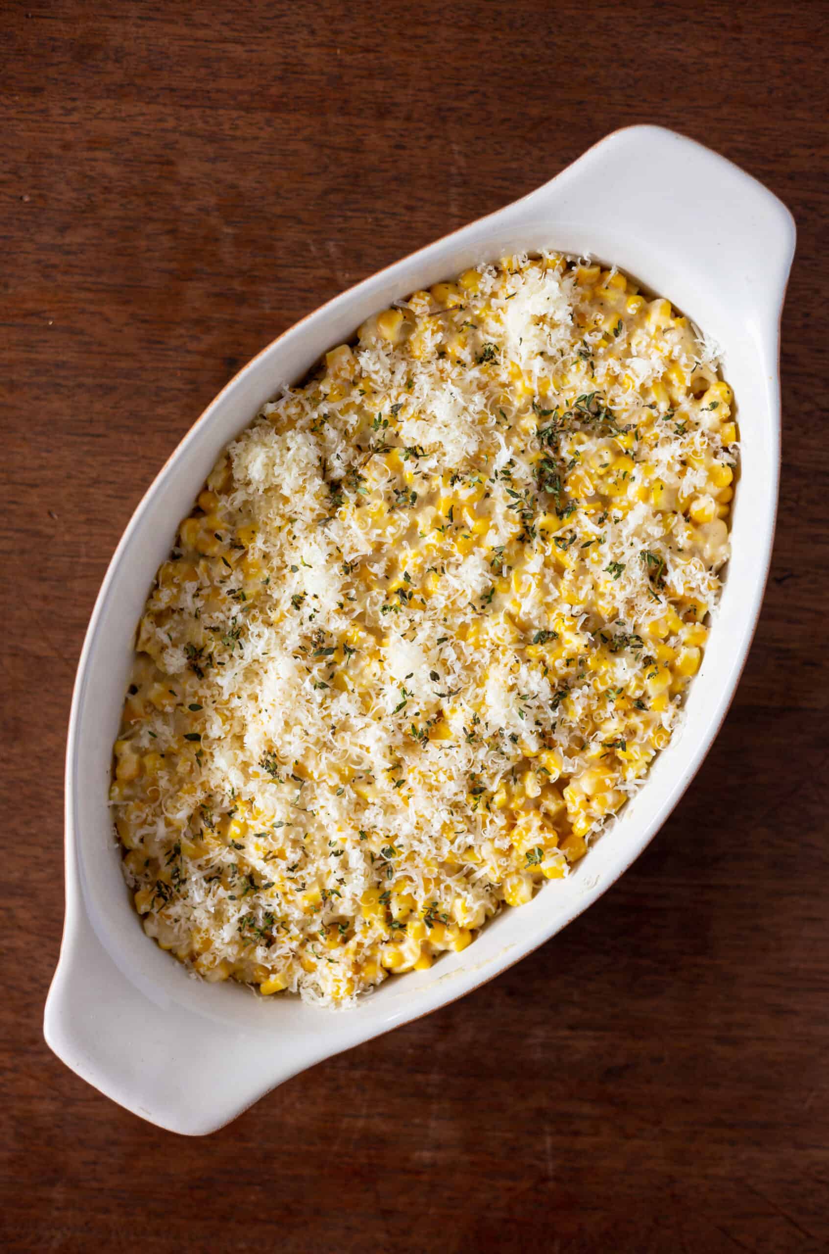 Creamed corn poured into casserole dish with parmesan cheese on top