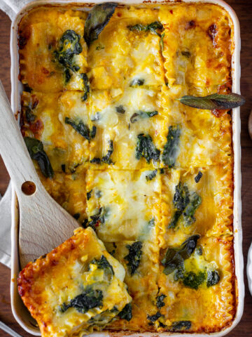 Spinach lasagna in a big dish with a serving spatula