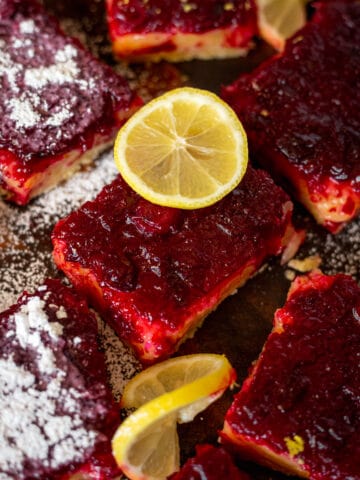 Lemon cranberry bars with powdered sugar and sliced lemons