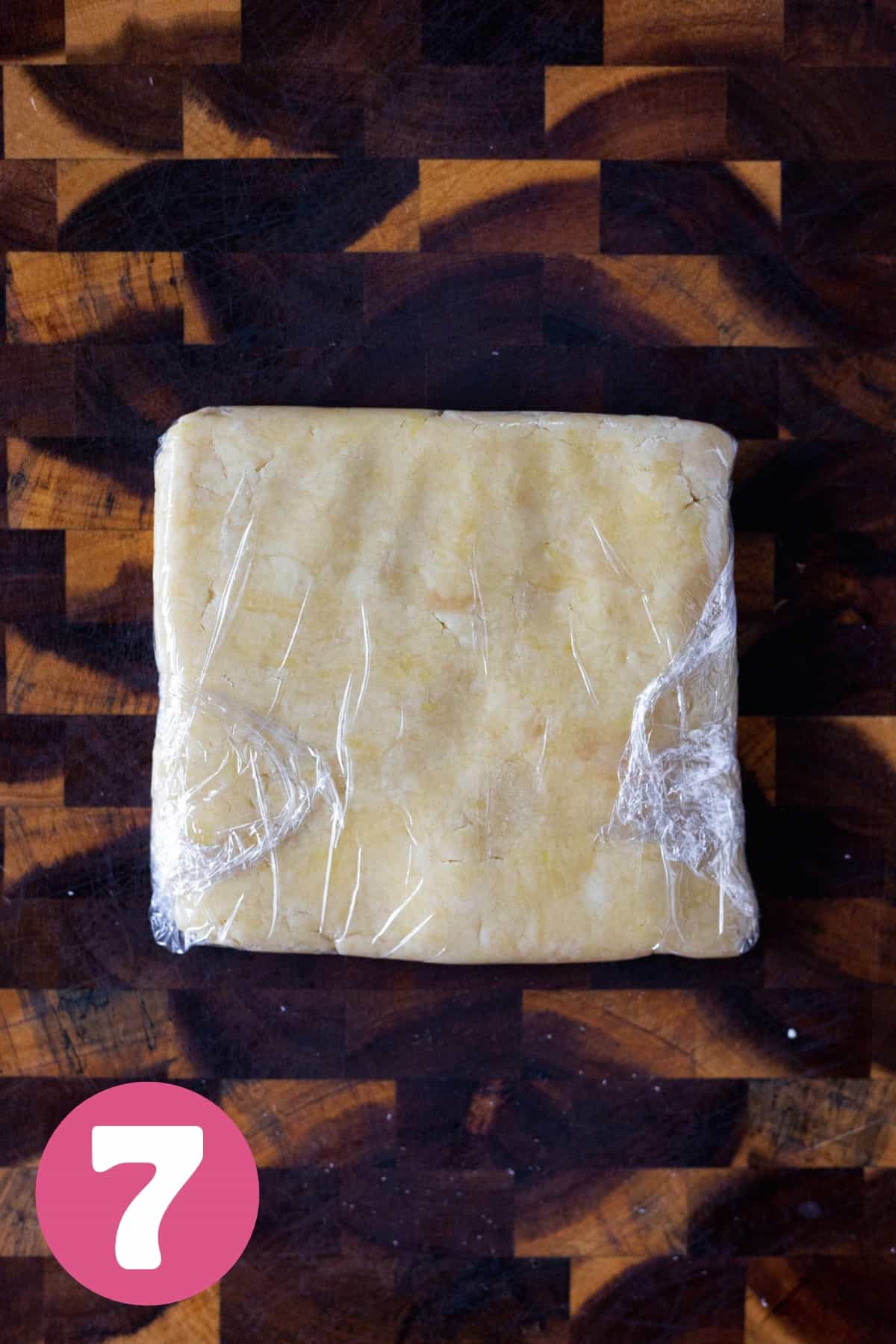 Apple tart dough in a square shape wrapped in plastic wrap