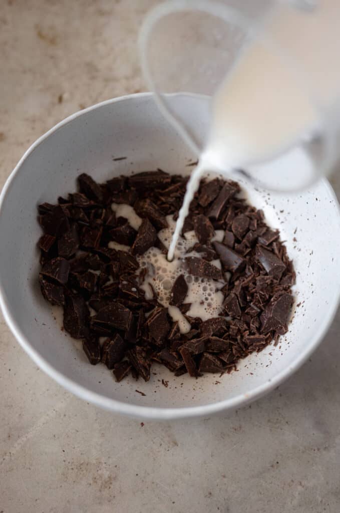 half and half being poured into a bowl with chopped chocolate