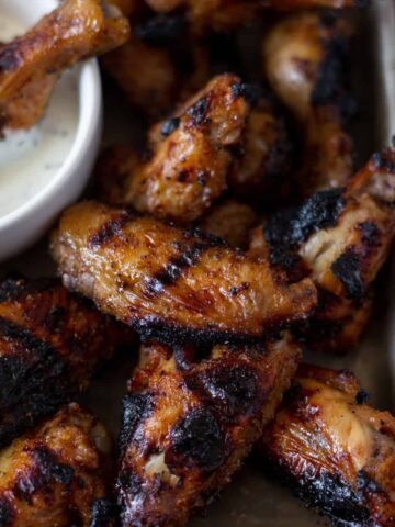 Close up of an apple cider brined chicken wing on a tray of other wings with a side of ranch