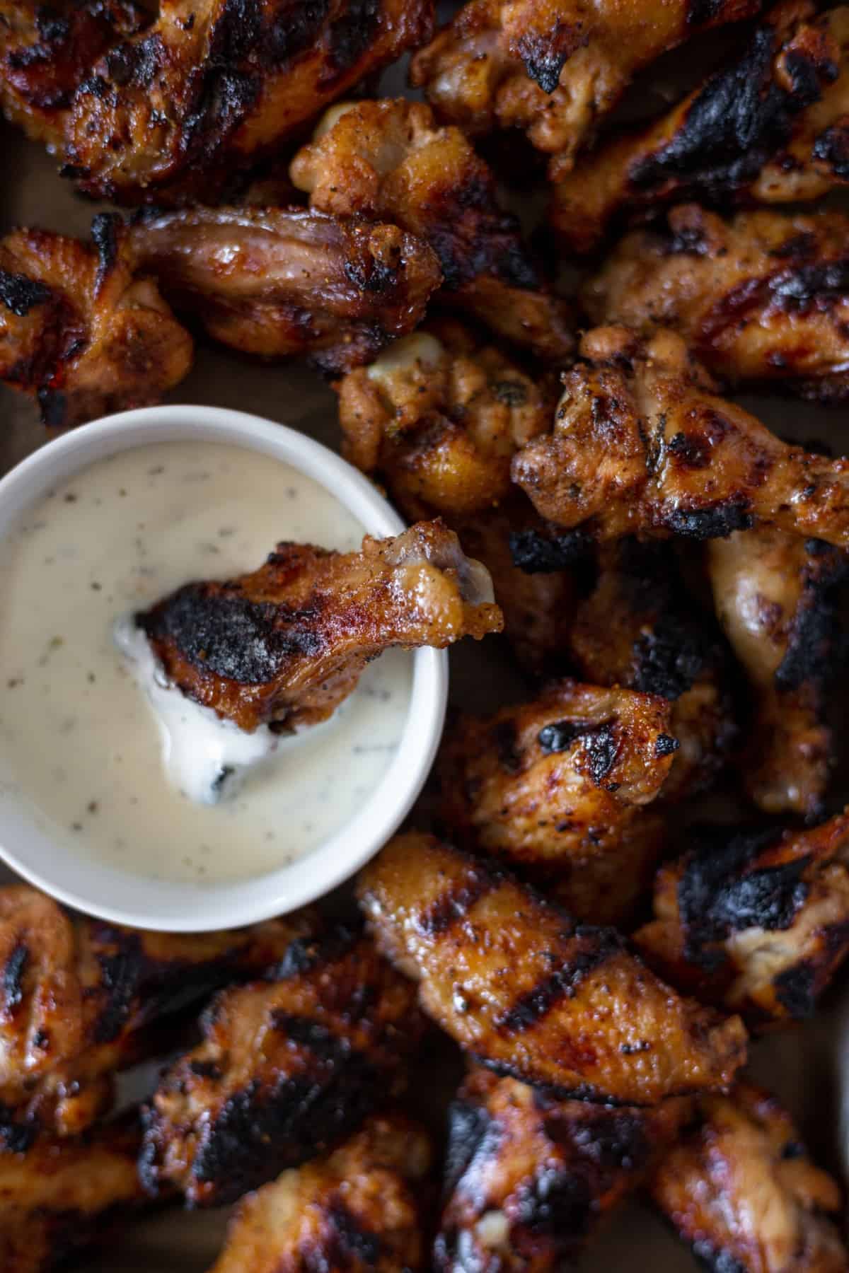A platter of grilled and brined chicken wings with a side of ranch