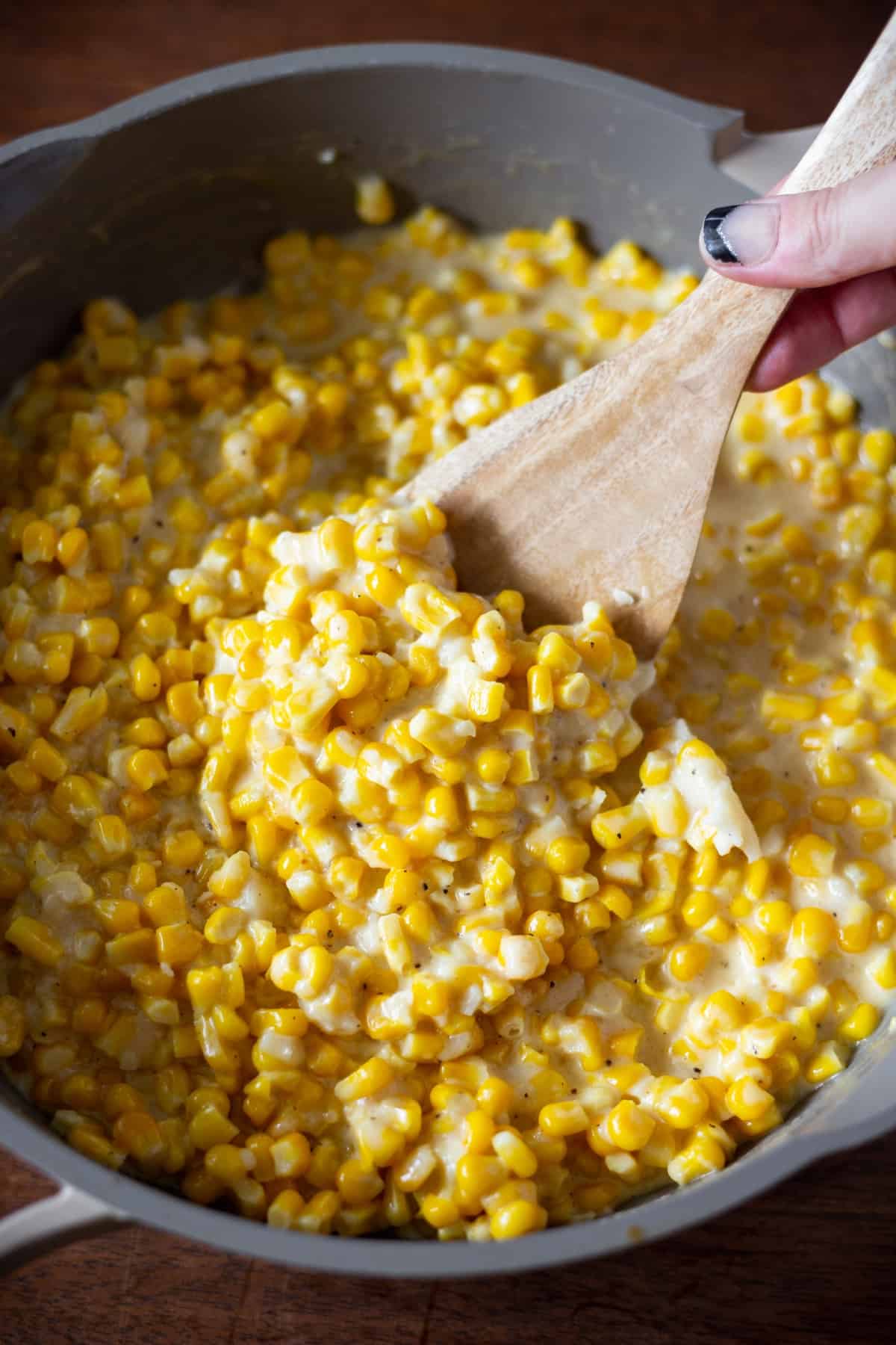 Large sauce pan of cream corn with a spoon in the center