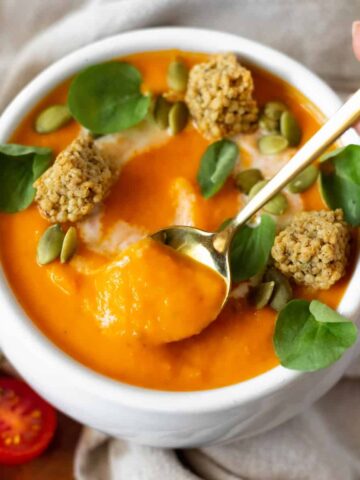 Bowl of butternut squash tomato soup with a spoon in it