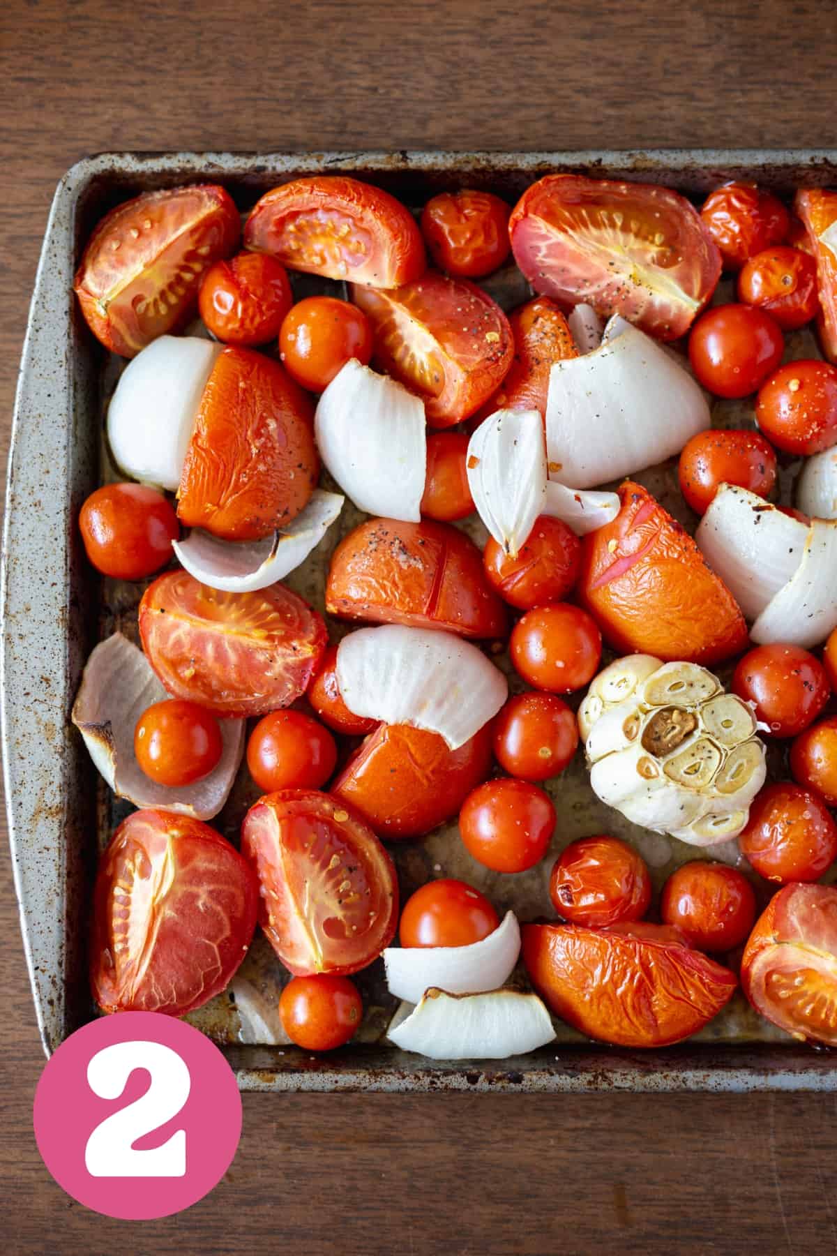 Tray of roasted tomatoes and onions and garlic with seasonings and oil