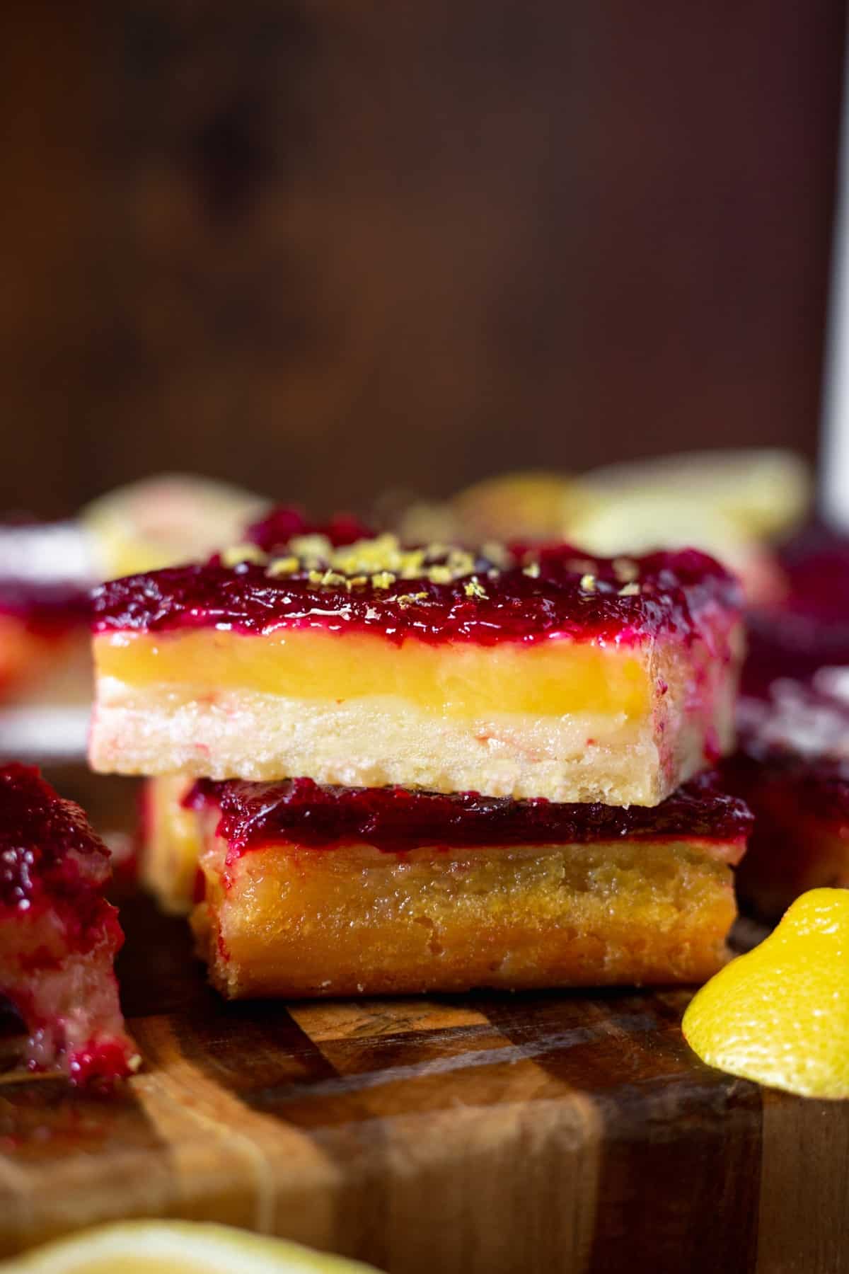 Lemon cranberry bars stacked upon one another on a cutting board