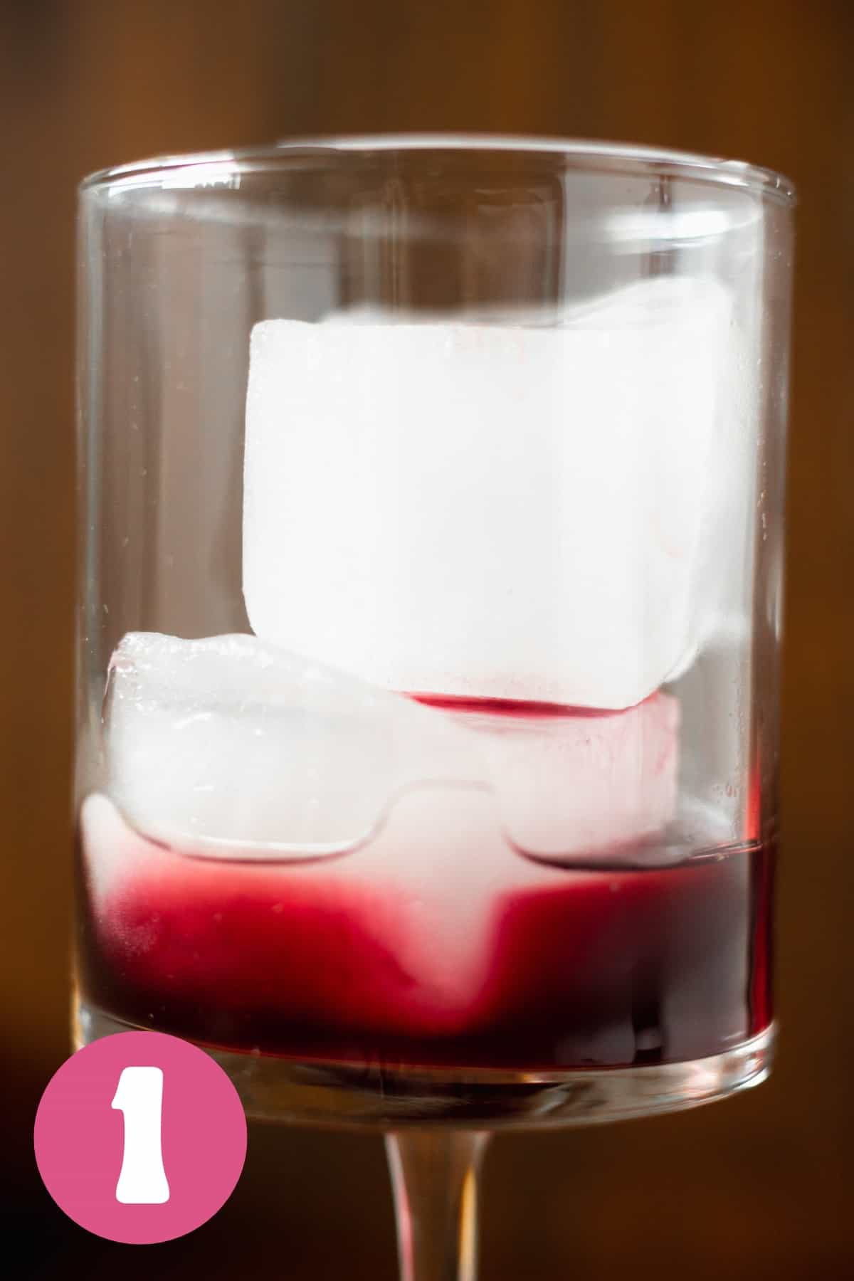 A martini glass with a shot of pomegranate juice labeled step 1