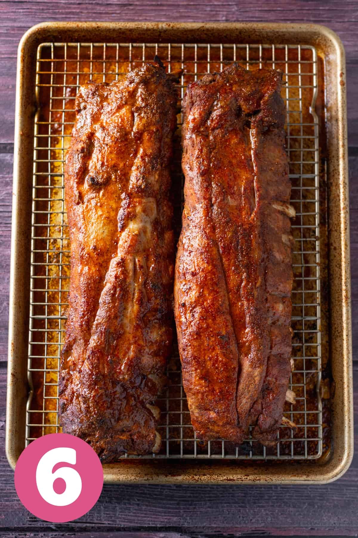 a sheet pan with a wire rack with two cooked racks of ribs