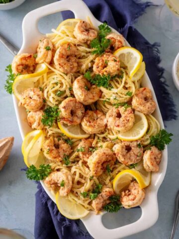 A platter of shrimp scampi with parsley and lemons