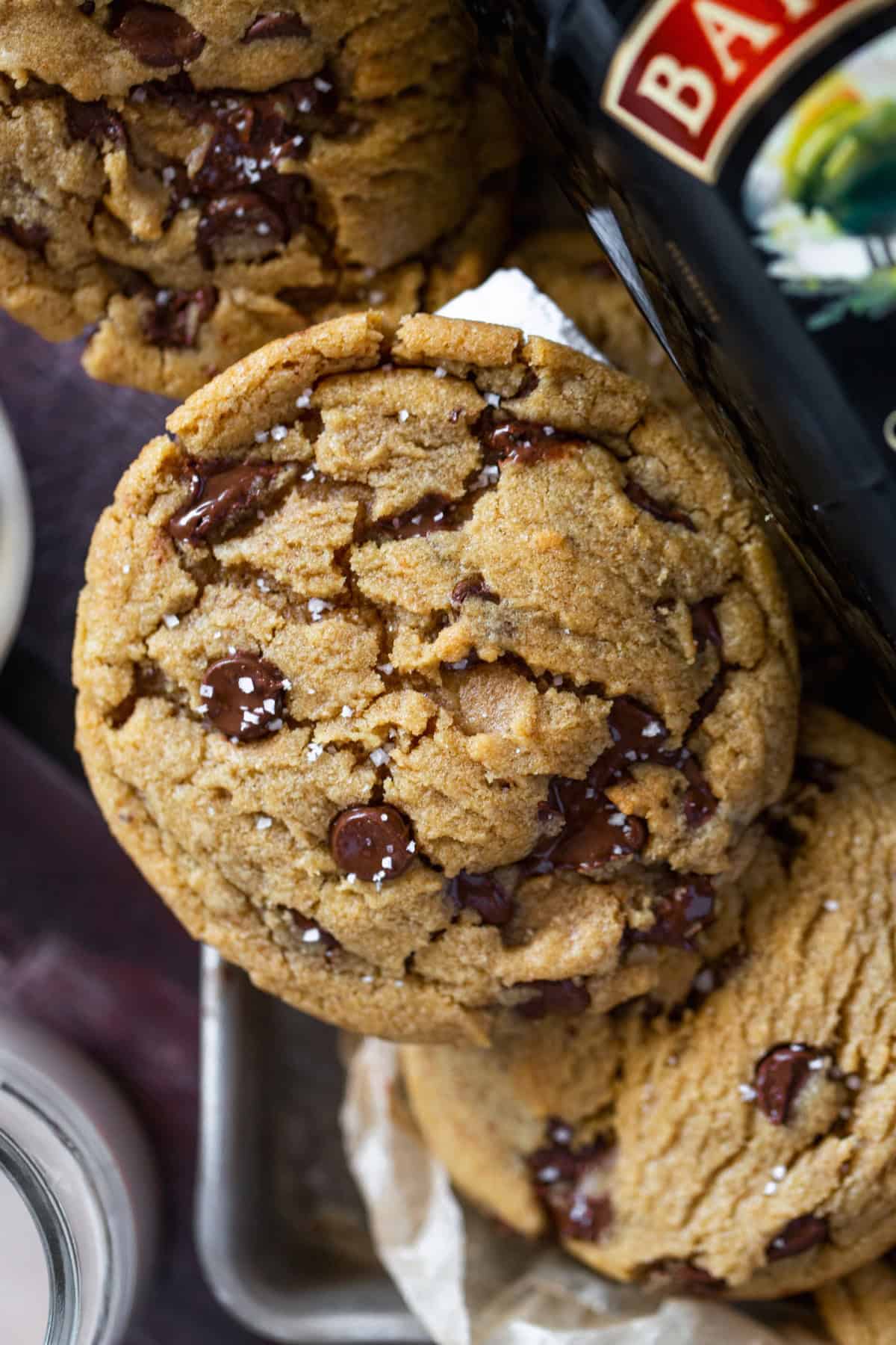 Cookie with chocolate chunks with milk on the side and baileys on a sheet pan