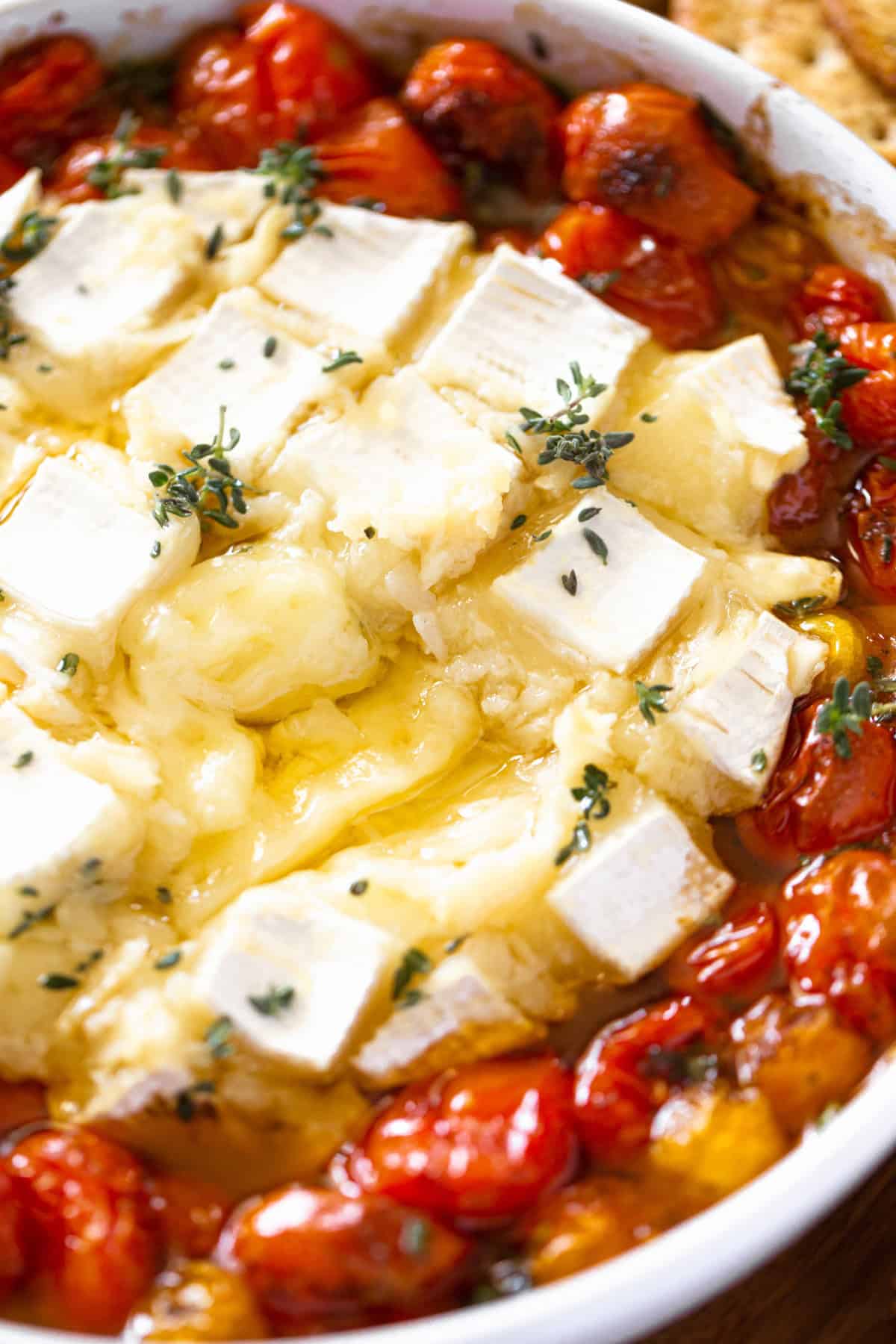 Brie that has been cut and is oozing out with roasted tomatoes