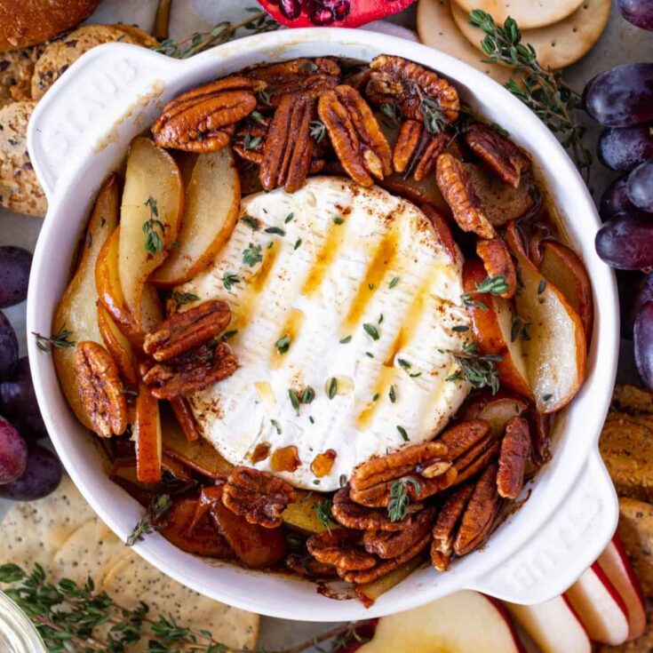 Pear Baked brie in a brie baker surrounded by fruit and crackers